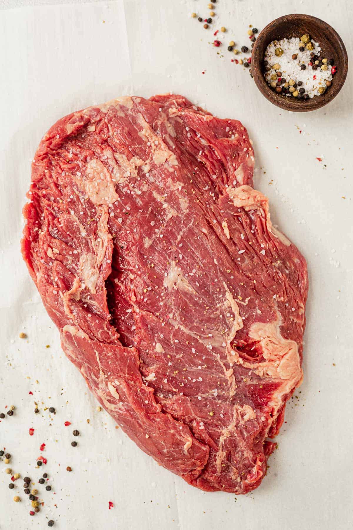 raw flank steak on a countertop with salt and pepper