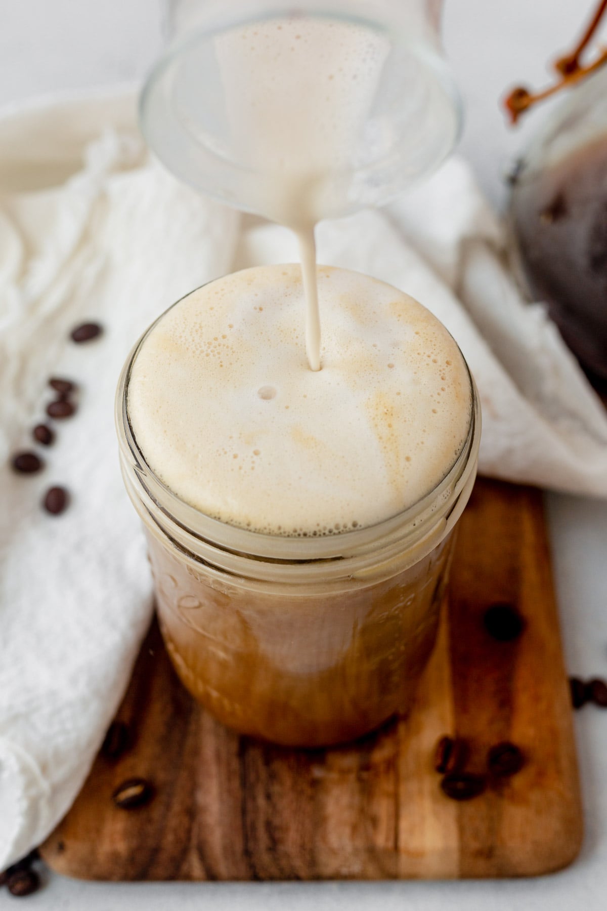 pouring vanilla sweet cream cold foam on top of cold brew